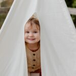 Happy little child smiling while peeking from tent