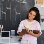 Girl in Pink and White Crew Neck T-shirt Holding Brown Notebook