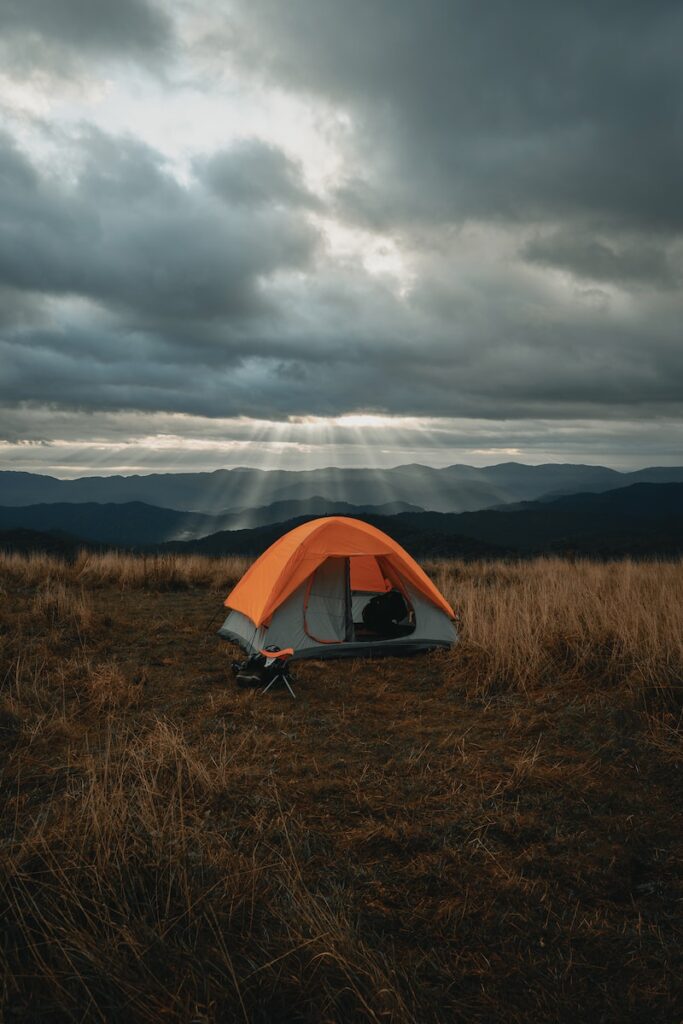 set-up gray and orange tent on brown field under cloudy sky