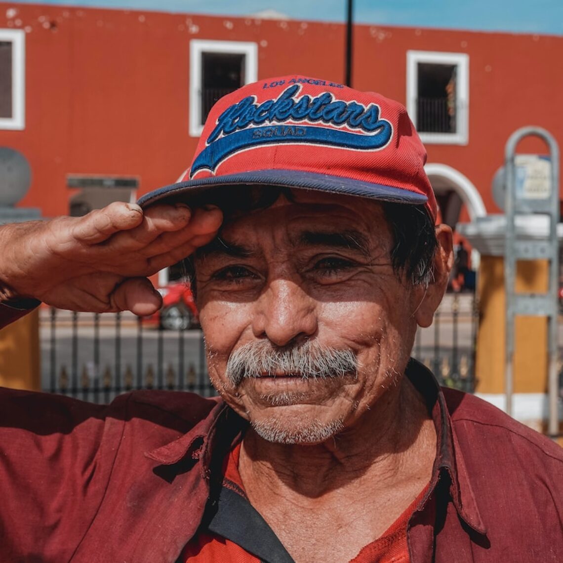 man in red button up shirt wearing black and red fitted cap