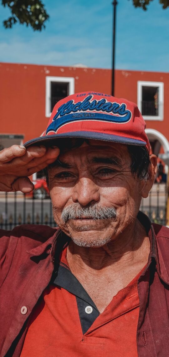 man in red button up shirt wearing black and red fitted cap